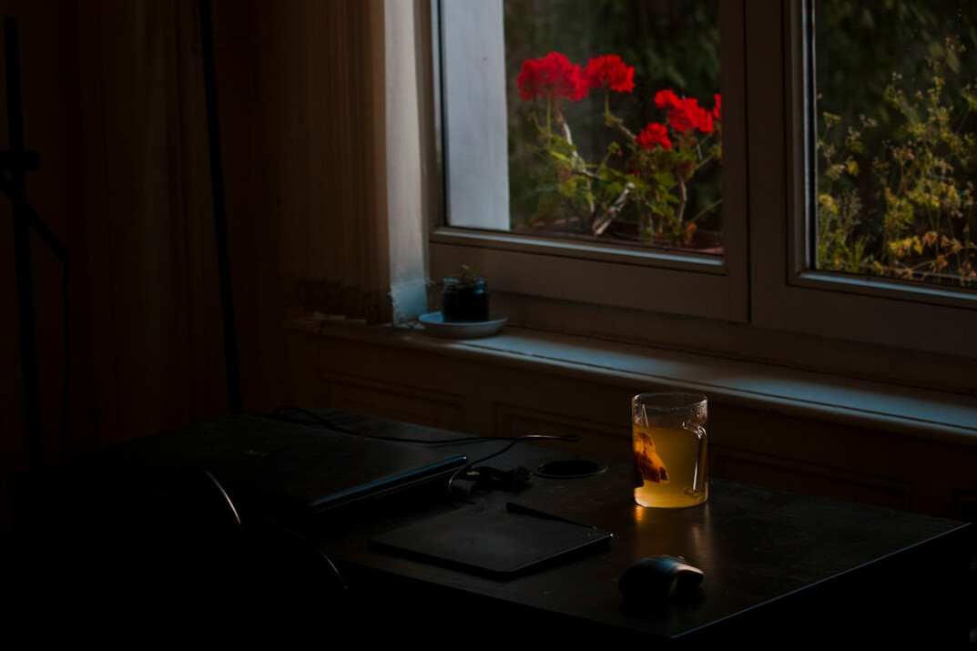 Desk with laptop, notebook and coffee in warm daylight